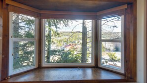 Ett hörnfenster med utsikt över träd och byggnader.