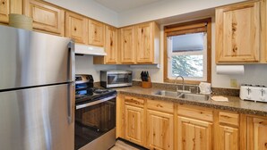 Una cucina moderna con mobili in legno, elettrodomestici in acciaio inossidabile e una finestra che permette l'illuminazione naturale.