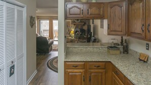 A kitchen with wooden cabinets, granite countertops, and a dining area with a chair and table. - 1 Mi to Dtwn Pigeon Forge! Mtn-view Gem w/ Balcony (Pigeon Forge)
