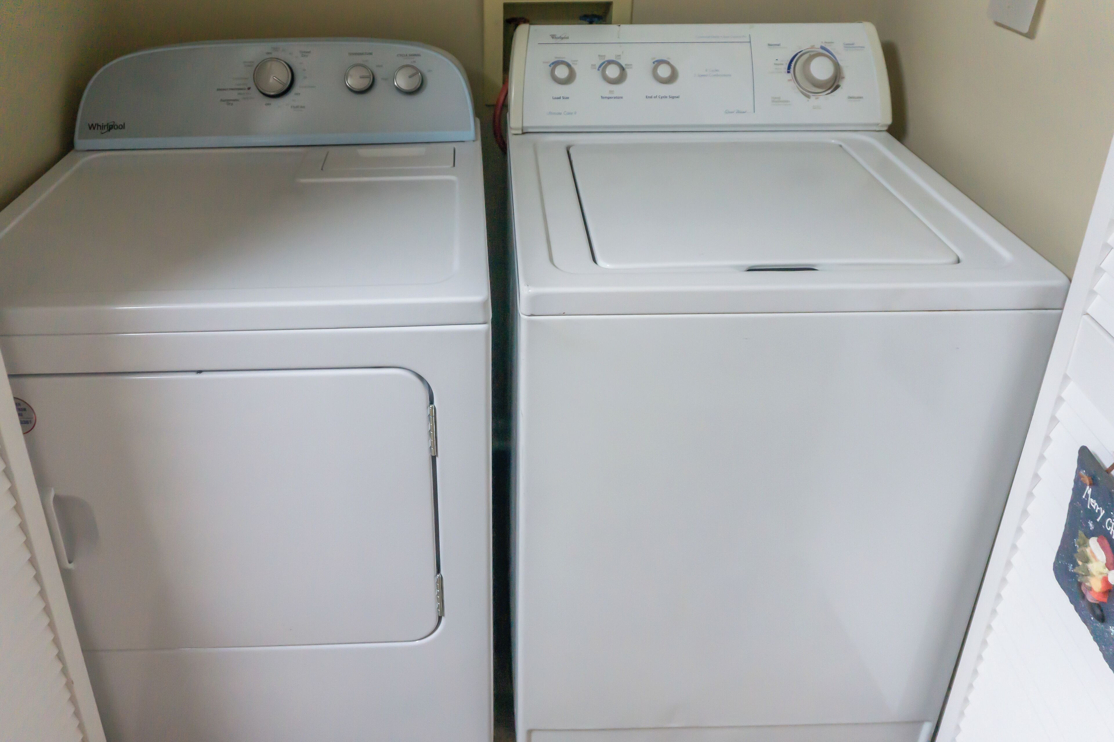 Two white Whirlpool front-loading washing machines in a laundry room.