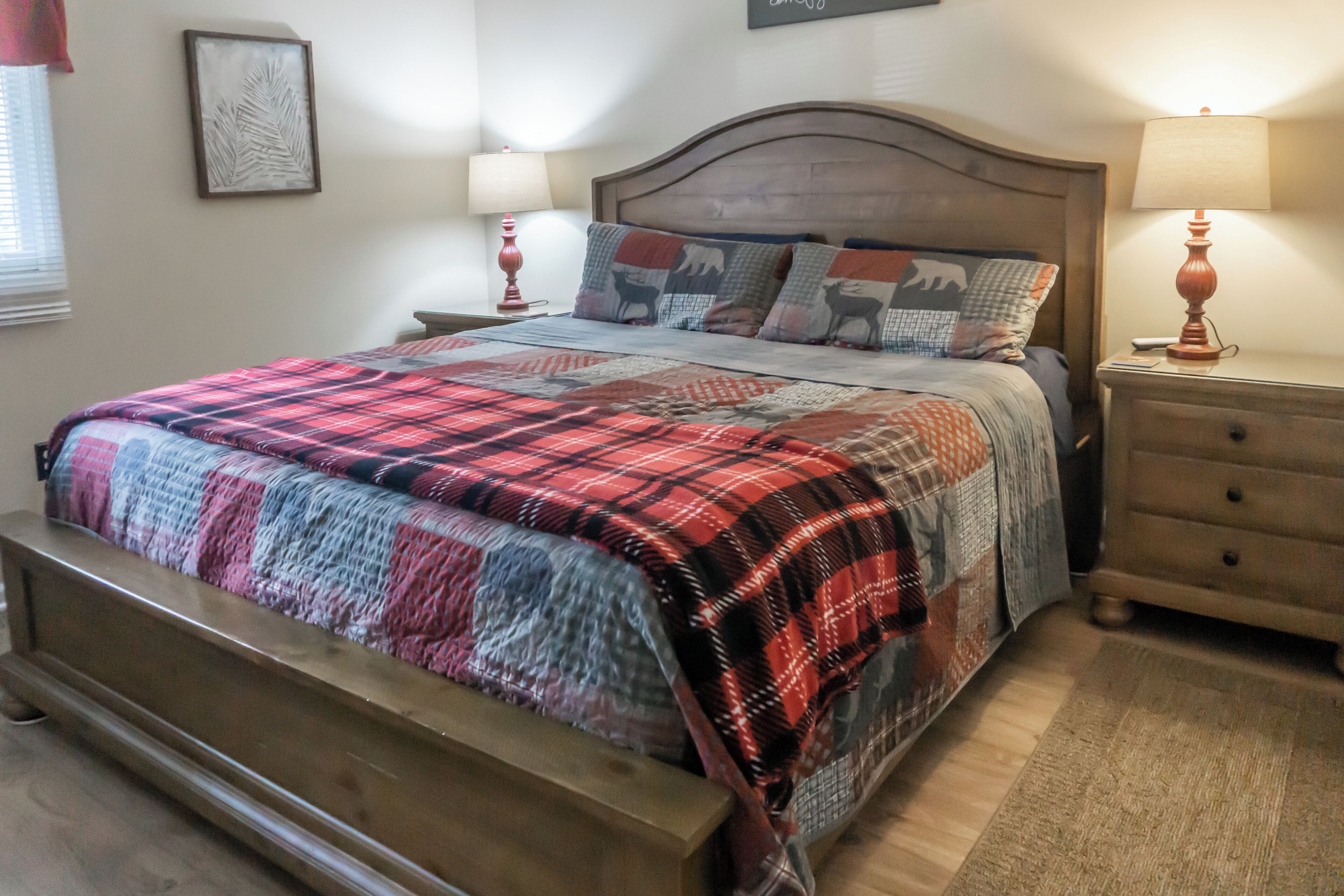 A bedroom with a wooden bed, a nightstand, a lamp, and a wall art piece.