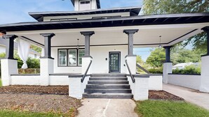 A two-story house with a covered porch, a front door, and a staircase leading to the entrance. - Historic Charm & Great Location! (Augusta)