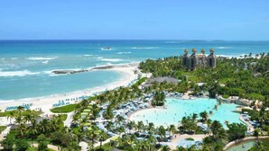 Een resort met een groot zwembad, strand en uitzicht op de oceaan.