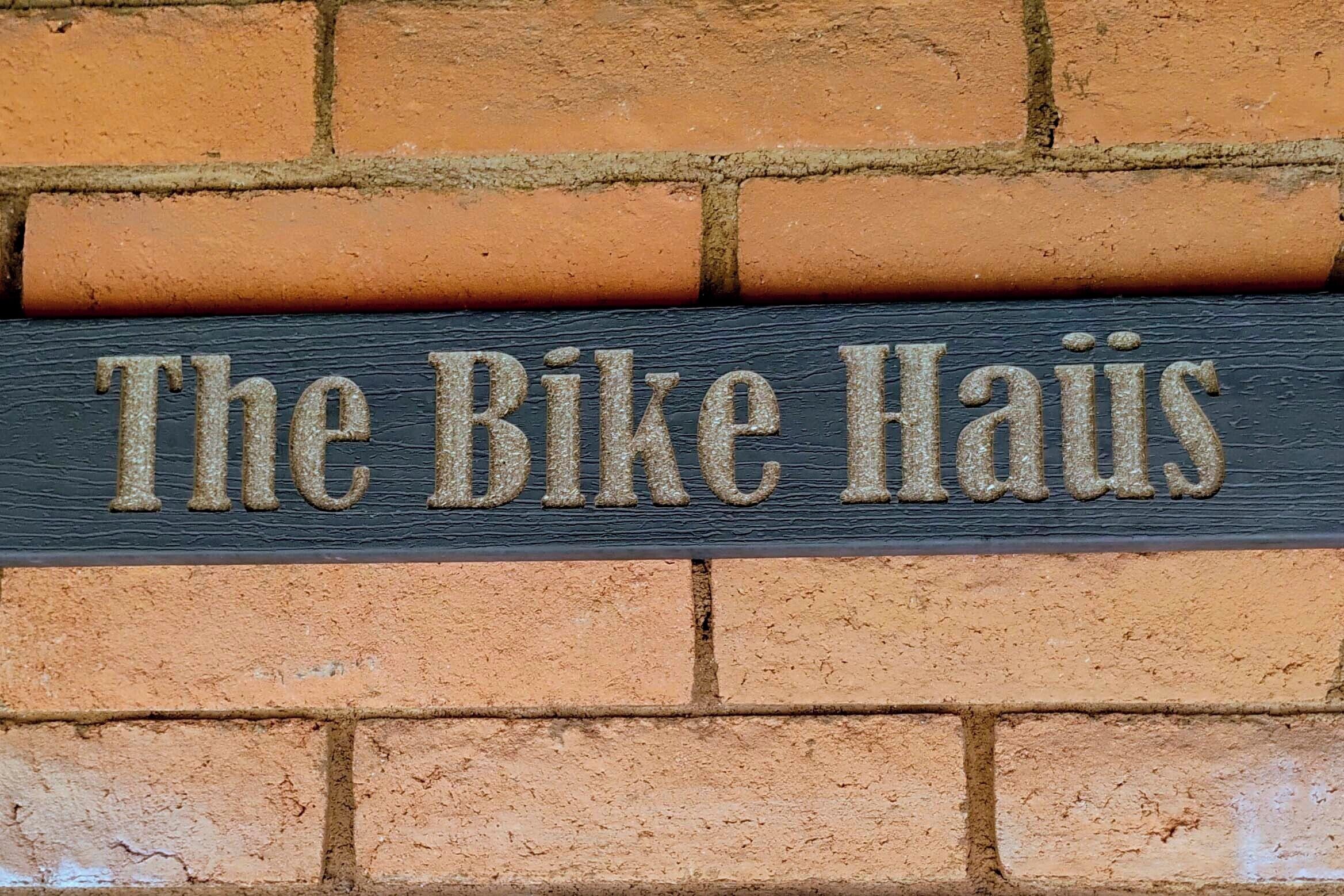 Um letreiro com o texto 'The Bike Haus' fixado numa parede de tijolos.