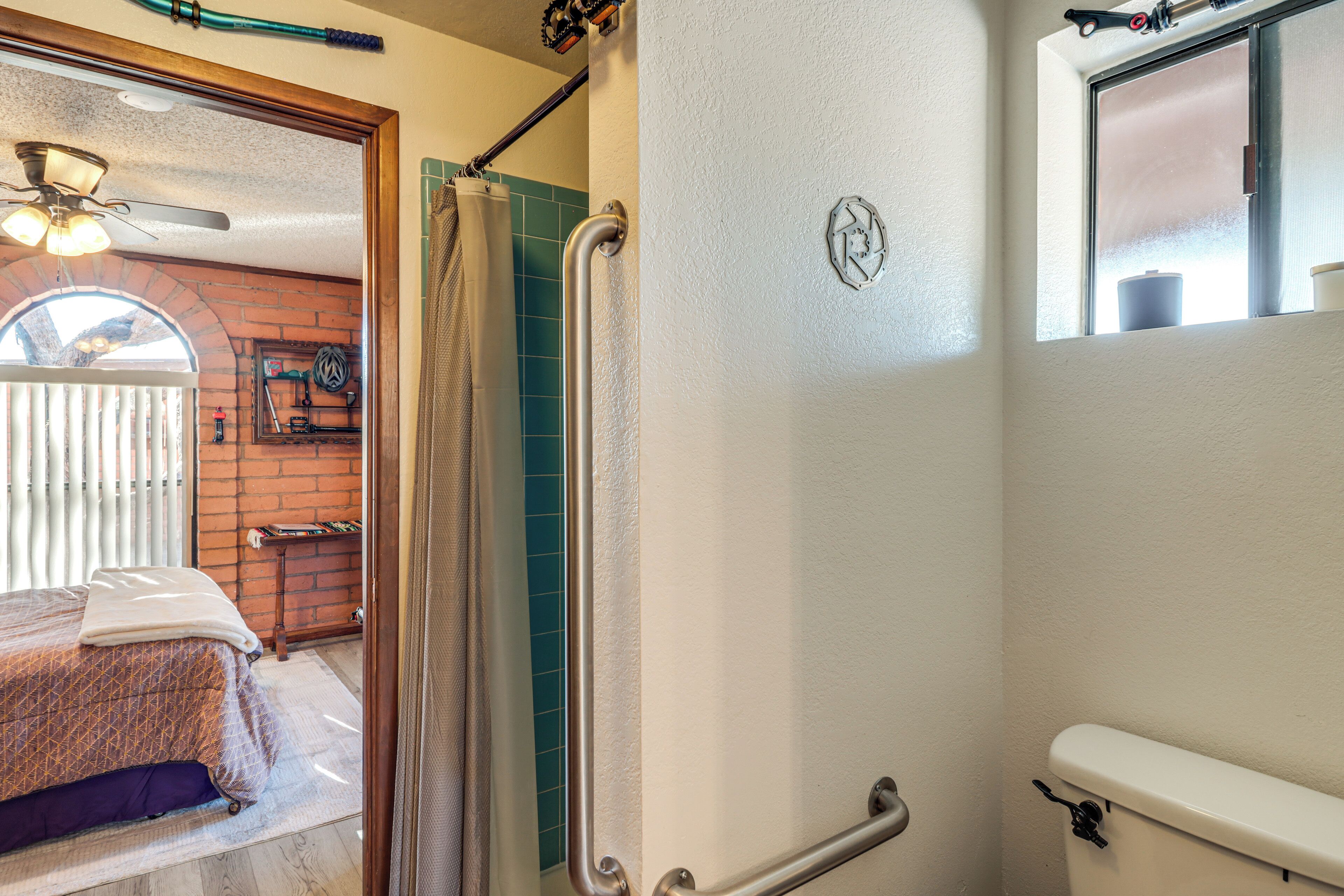 A bathroom with a shower, a toilet, and a window.