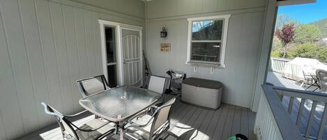 A covered porch with a table and chairs, a bench, a trash can, and a sign that says "HAPPY PLACE".
