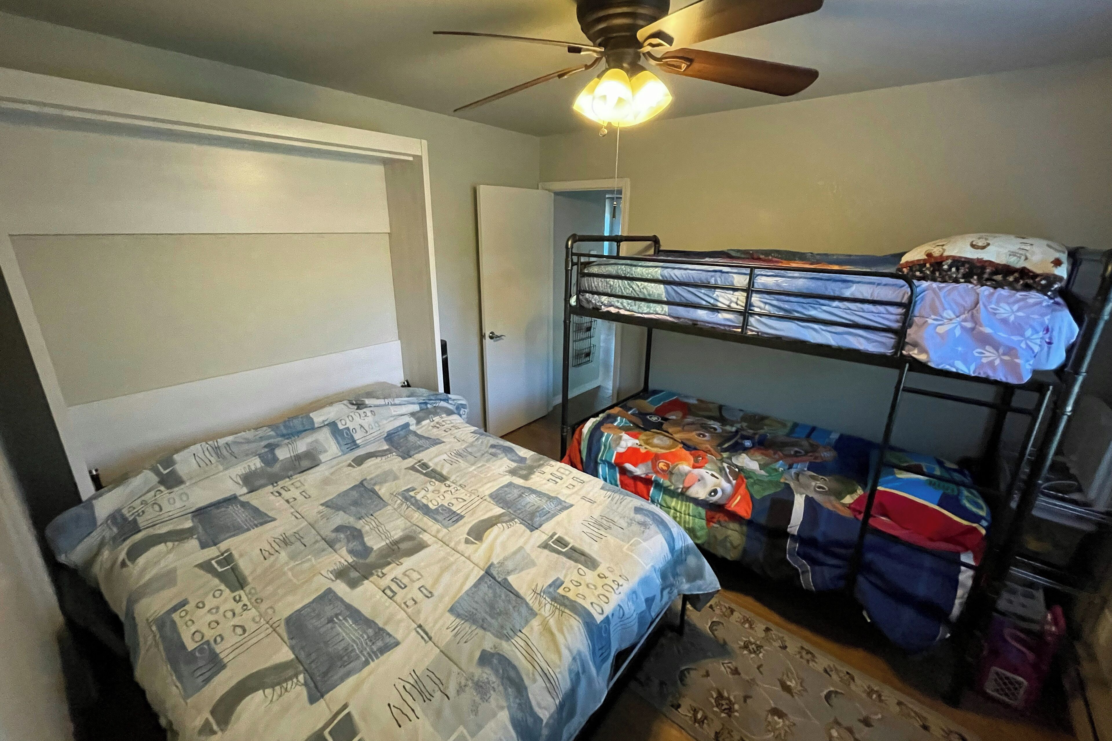 A bedroom with a bunk bed, a single bed, and a ceiling fan.