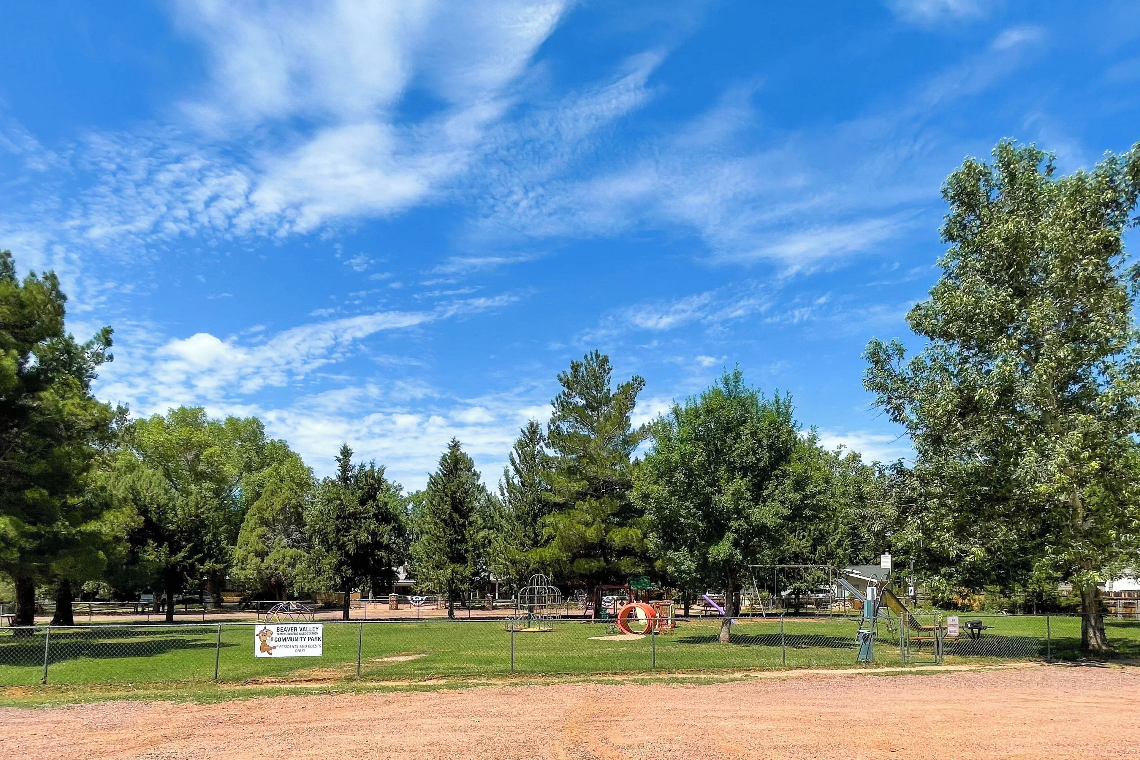 A park with playground equipment, a dirt path, and a sign for Beaver Valley Community Park.