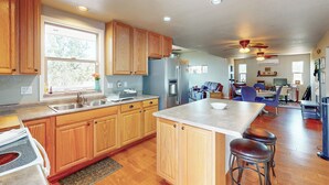 A spacious kitchen with wooden cabinets, a large island, and a dining area with blue chairs. - Dog-friendly Payson Retreat w/ Panoramic Views! (Payson)