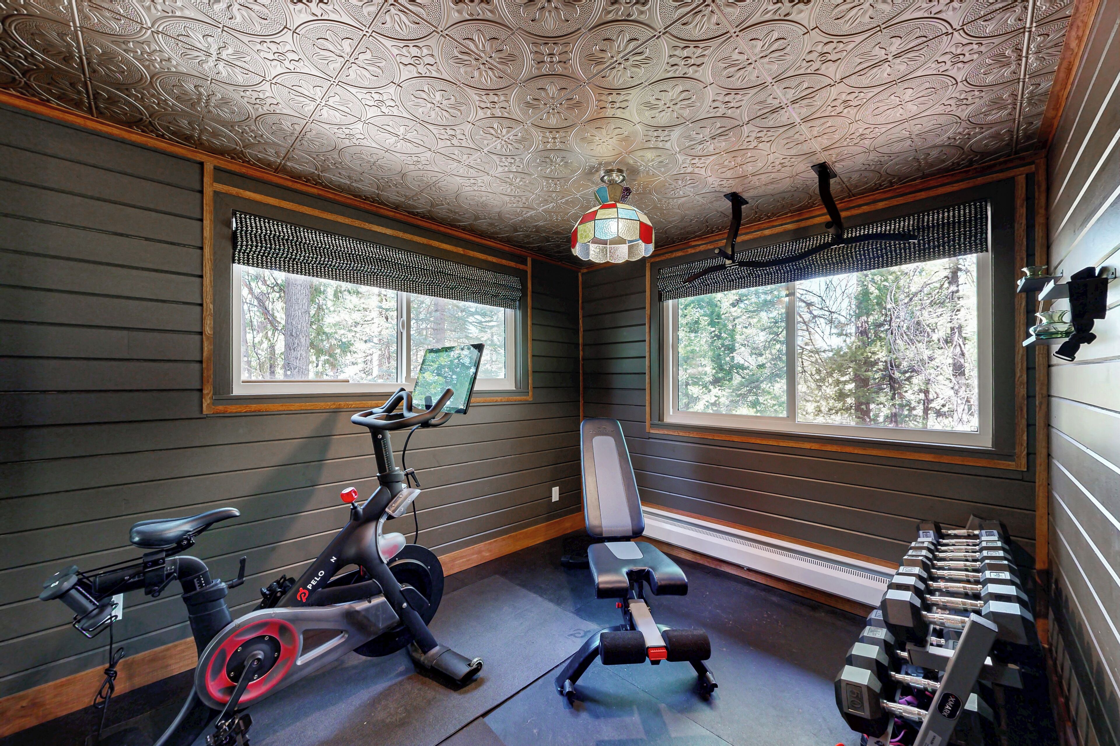 Une salle de sport équipée de matériel d’exercice, dotée de grandes fenêtres et ornée d’un plafond décoratif.