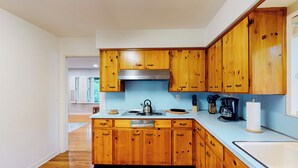 A kitchen with wooden cabinets, a stainless steel range hood, a kettle, and a coffee maker. - Steps to Lake Hollingsworth! Dog-friendly Retreat (Lakeland)