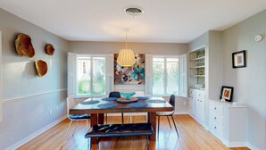 A dining area with a wooden table, benches, and a decorative wall piece. - Steps to Lake Hollingsworth! Dog-friendly Retreat (Lakeland)