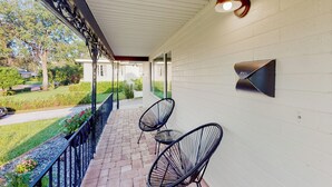 A covered outdoor area with a brick floor, two black wire-framed chairs, a mailbox, and a wall-mounted light fixture. - Steps to Lake Hollingsworth! Dog-friendly Retreat (Lakeland)