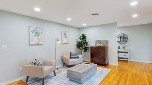 A modern living room with a beige sofa, a coffee table, and a wooden cabinet. - Steps to Lake Hollingsworth! Dog-friendly Retreat (Lakeland)