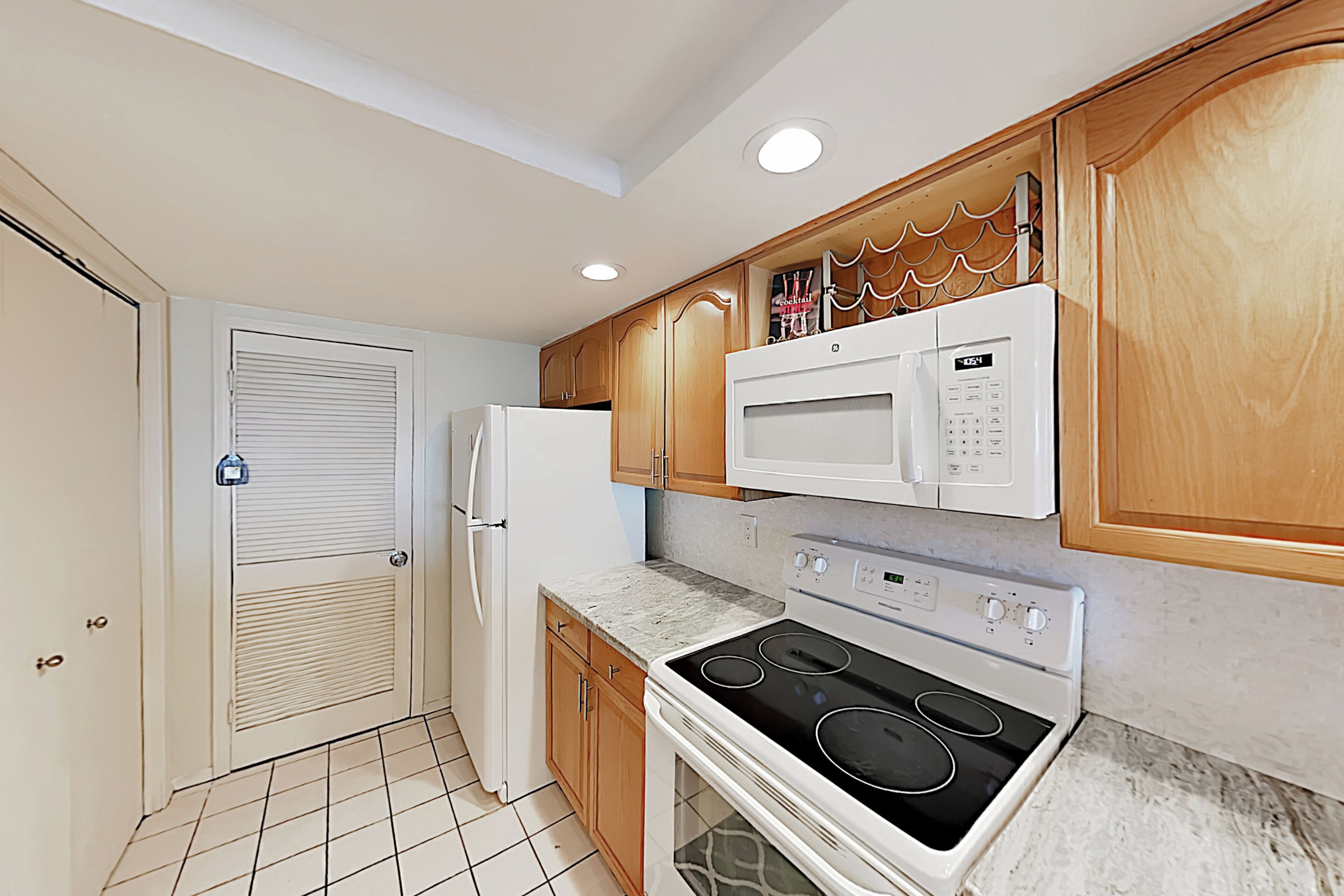 A kitchen with a refrigerator, microwave, stove, and wooden cabinets.