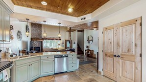 A spacious kitchen with a large island, built-in appliances, and a stone backsplash. - Steps to Brian Head Resort: Ski Home w/ Games (Brian Head)