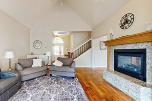 A spacious living room with a fireplace, a staircase, and a large rug. - Hot Tub & Deck! Outdoor Basecamp in Klamath Falls (Klamath Falls)