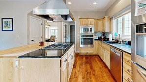A modern kitchen with wooden cabinets, stainless steel appliances, and a central island. - Hot Tub & Deck! Outdoor Basecamp in Klamath Falls (Klamath Falls)