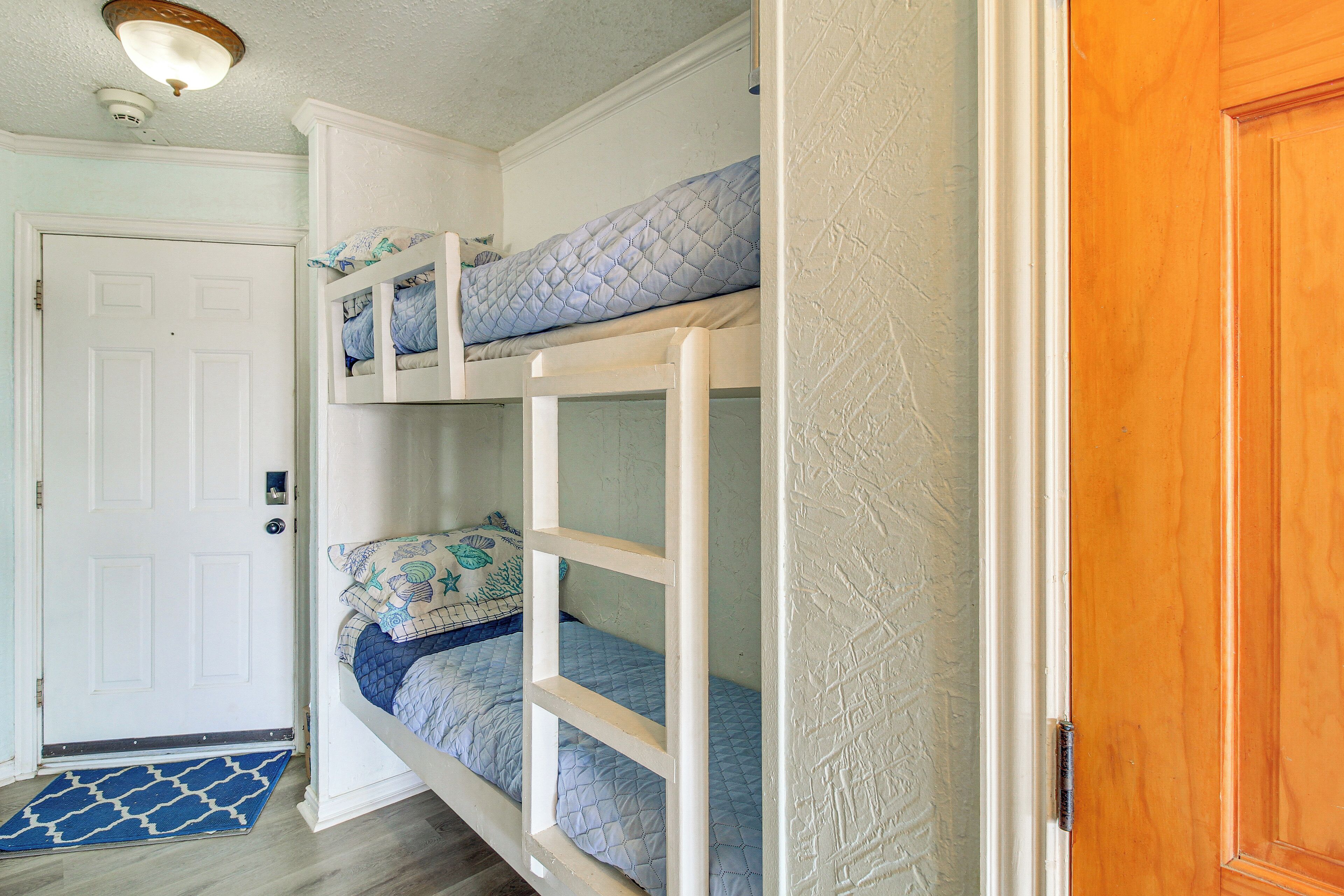 A room with bunk beds, a white door, and a wooden door.