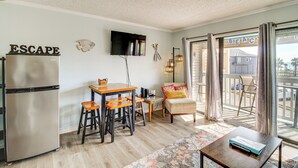 Een compacte woonruimte met kitchenette, een eethoek, een bank en een balkon met uitzicht op het strand.