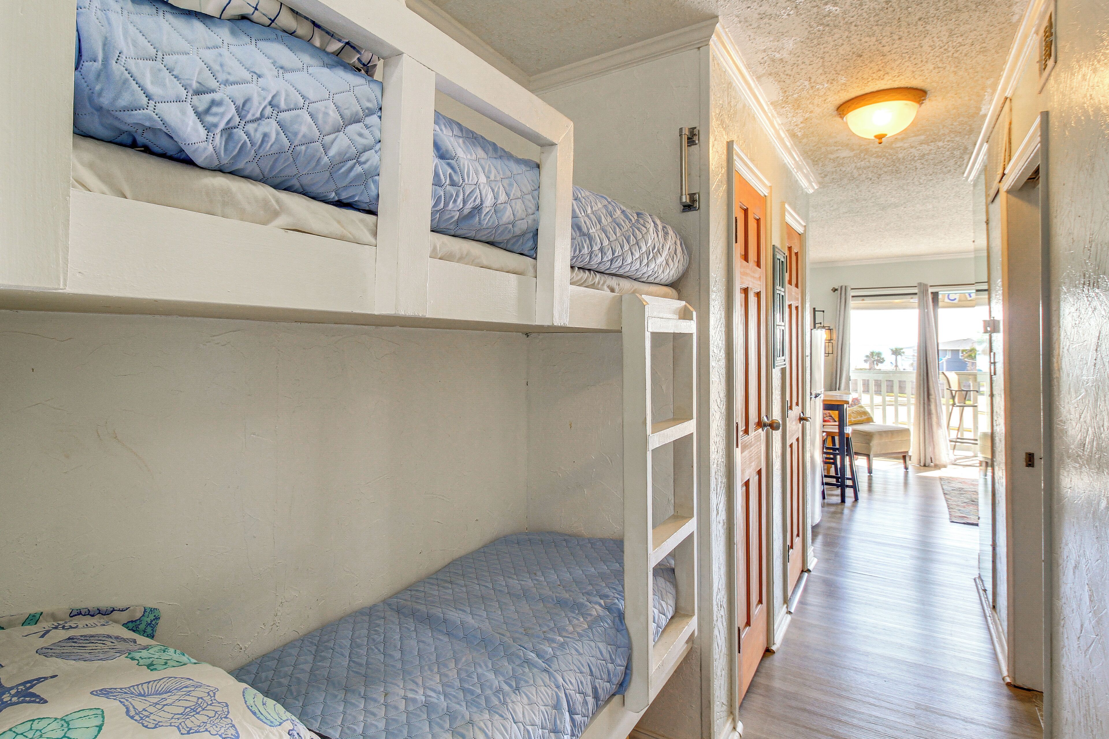 Ein Zimmer mit Etagenbetten, Holzboden und einem Flur, der zu einem Außenbereich führt.