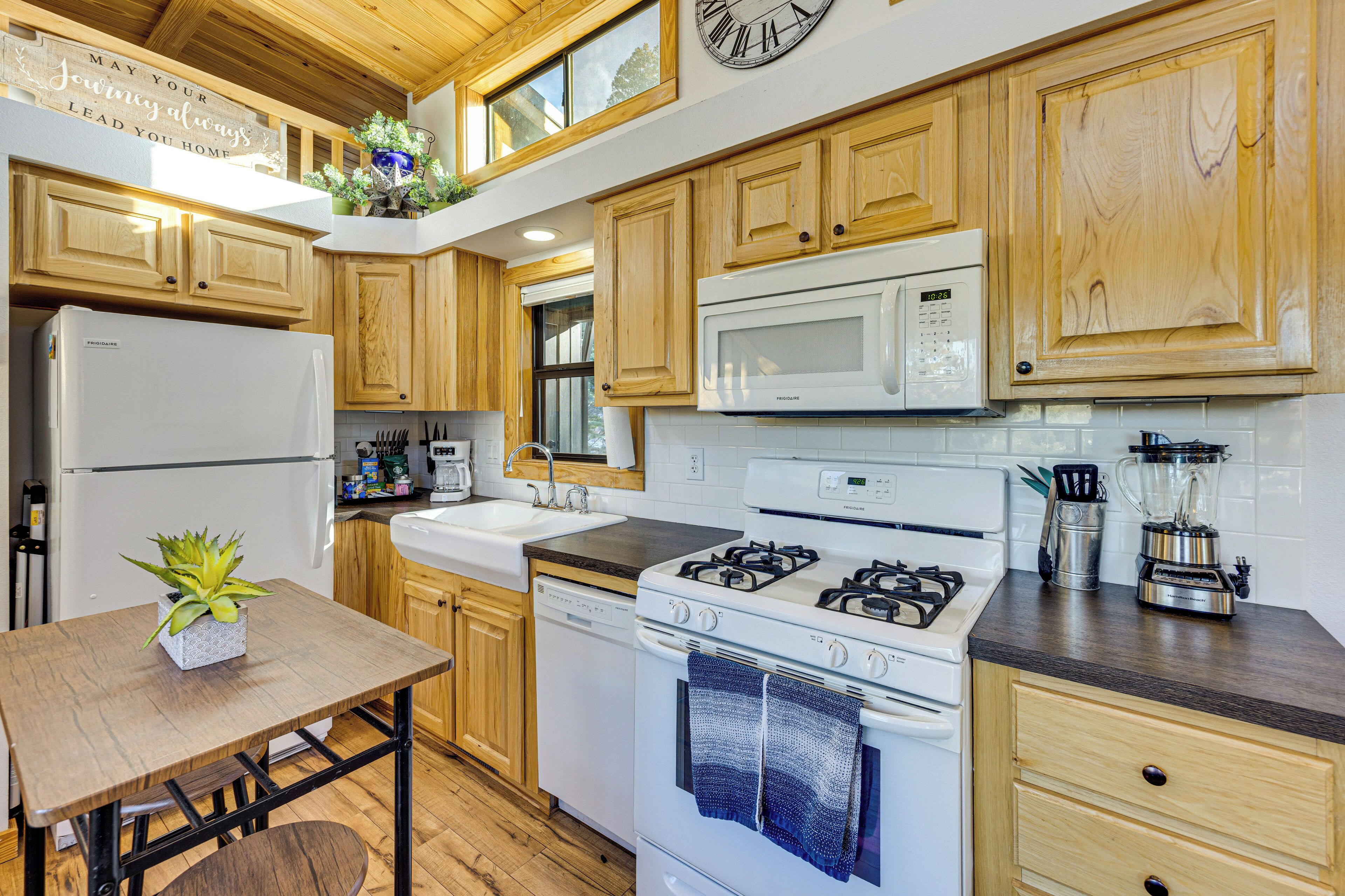 A kitchen with wooden cabinets, a white refrigerator, a stove, a microwave, and a sink.