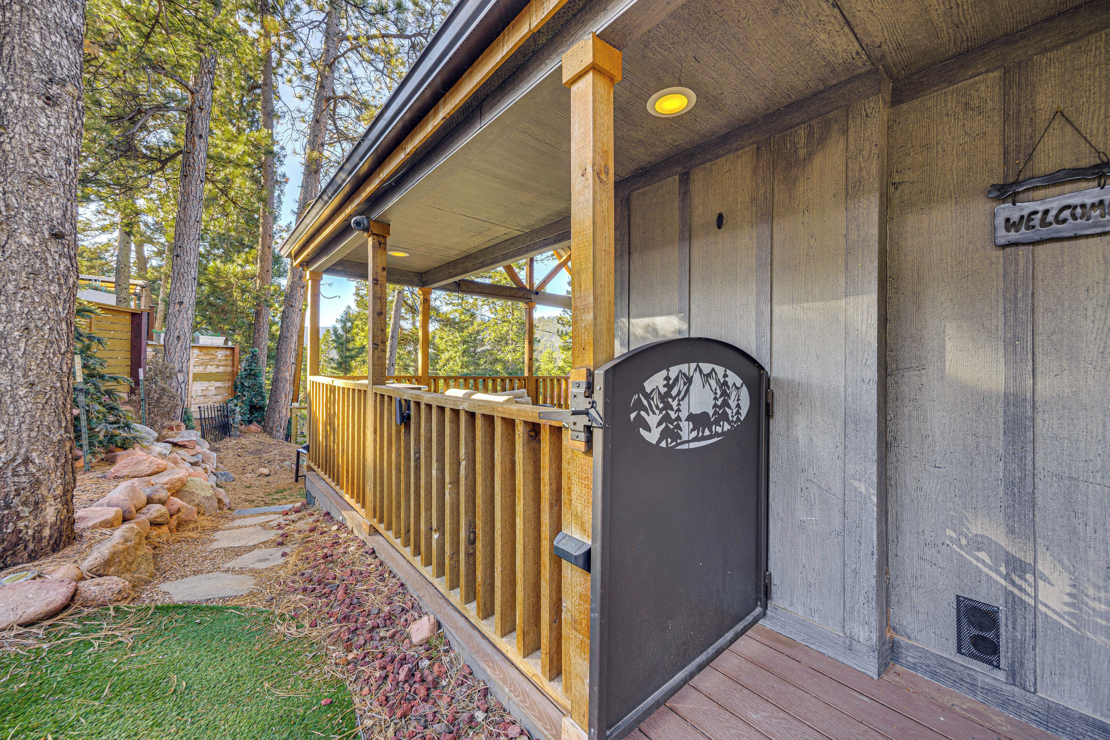 A wooden deck with a metal gate, a welcome sign, and a stone pathway leading to a building.