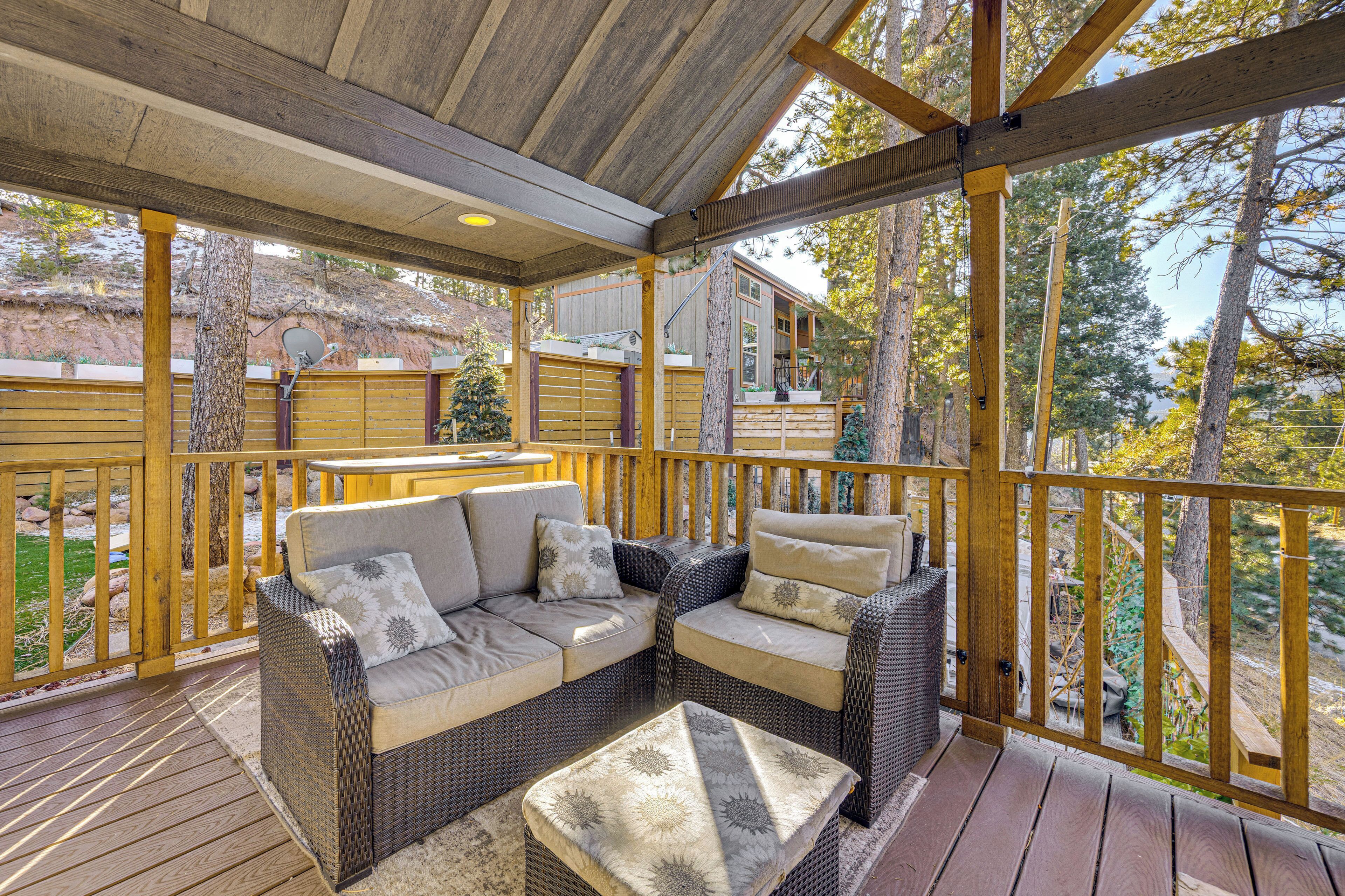 A covered deck with wicker furniture and a view of a house.