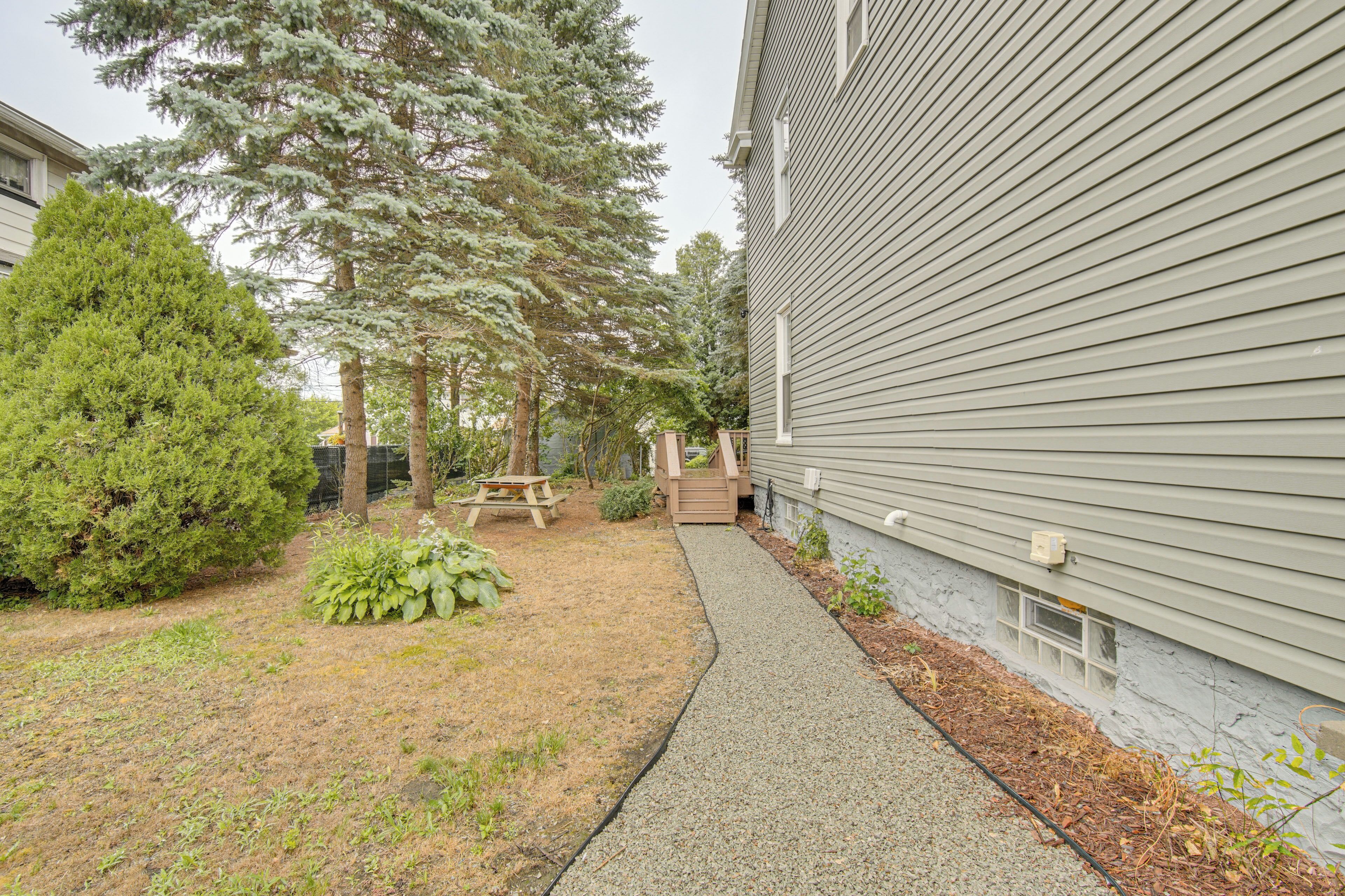 A residential building with a gravel pathway, a picnic table, and various trees.