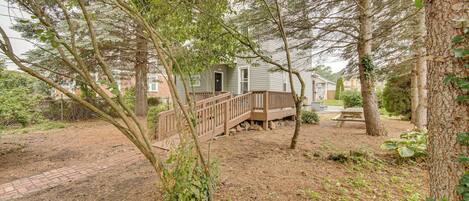 A wooden deck leading to a house surrounded by trees.