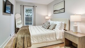 A bedroom with a bed, bedside lamps, a mirror, and a window with curtains. - Game Room & Backyard: Modern Altoona Home! (Altoona)