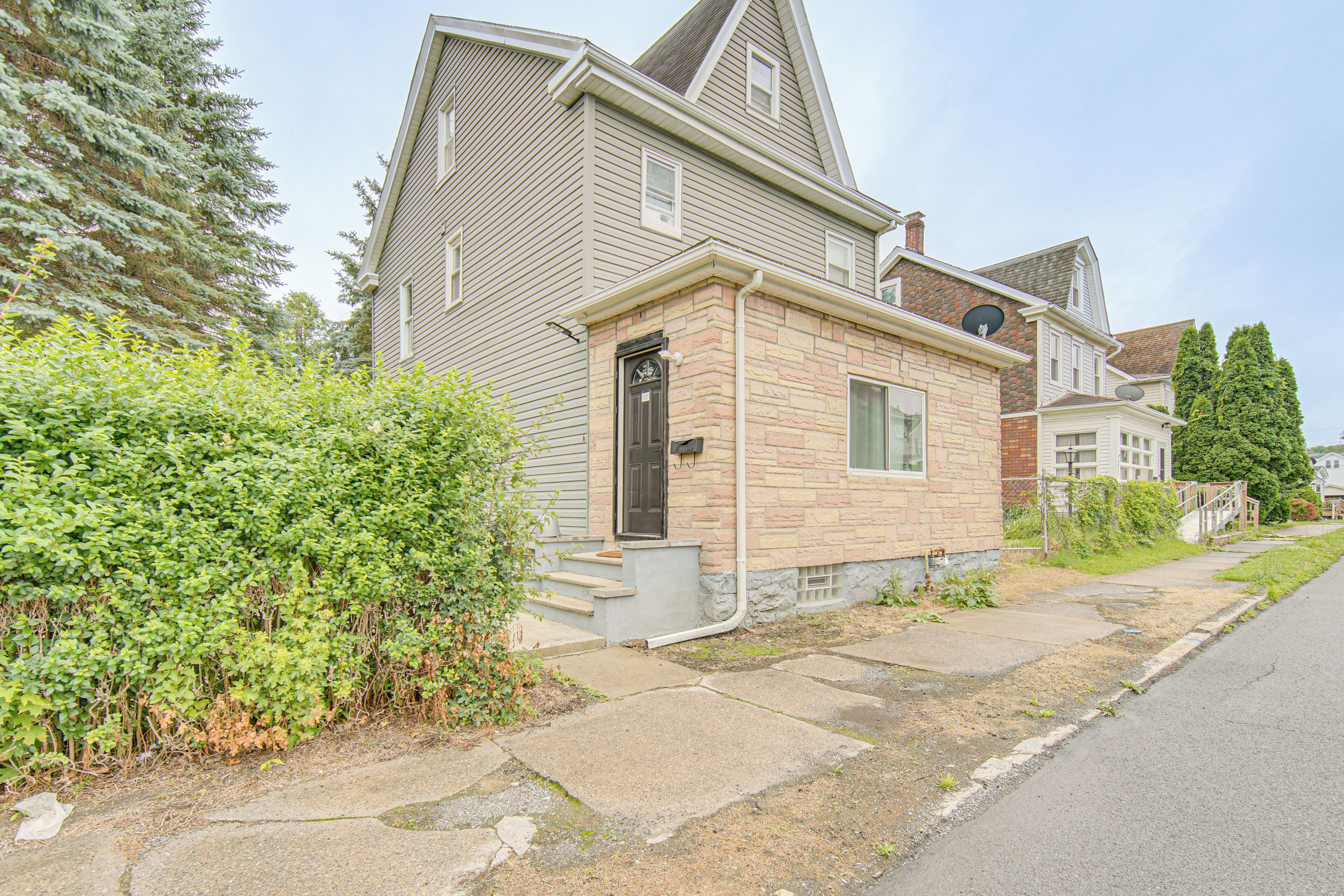 A residential house with a front porch, a small attached garage, and a driveway.