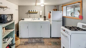 A compact kitchen with white cabinets, a stove, a refrigerator, and a window with a basket on the sill. - Couples Haven 1 Mi to Dtwn Dolores! Bring Your Pet (Dolores)