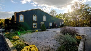 A two-story building with a dark facade, a front entrance, and a small front yard with gravel and plants. - Hot Tub, Lake Monroe Views! 22-acre Outdoor Oasis (Bloomington)