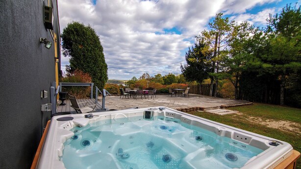 A hot tub with a patio area, surrounded by trees and a grassy lawn. - Hot Tub, Lake Monroe Views! 22-acre Outdoor Oasis (Bloomington)