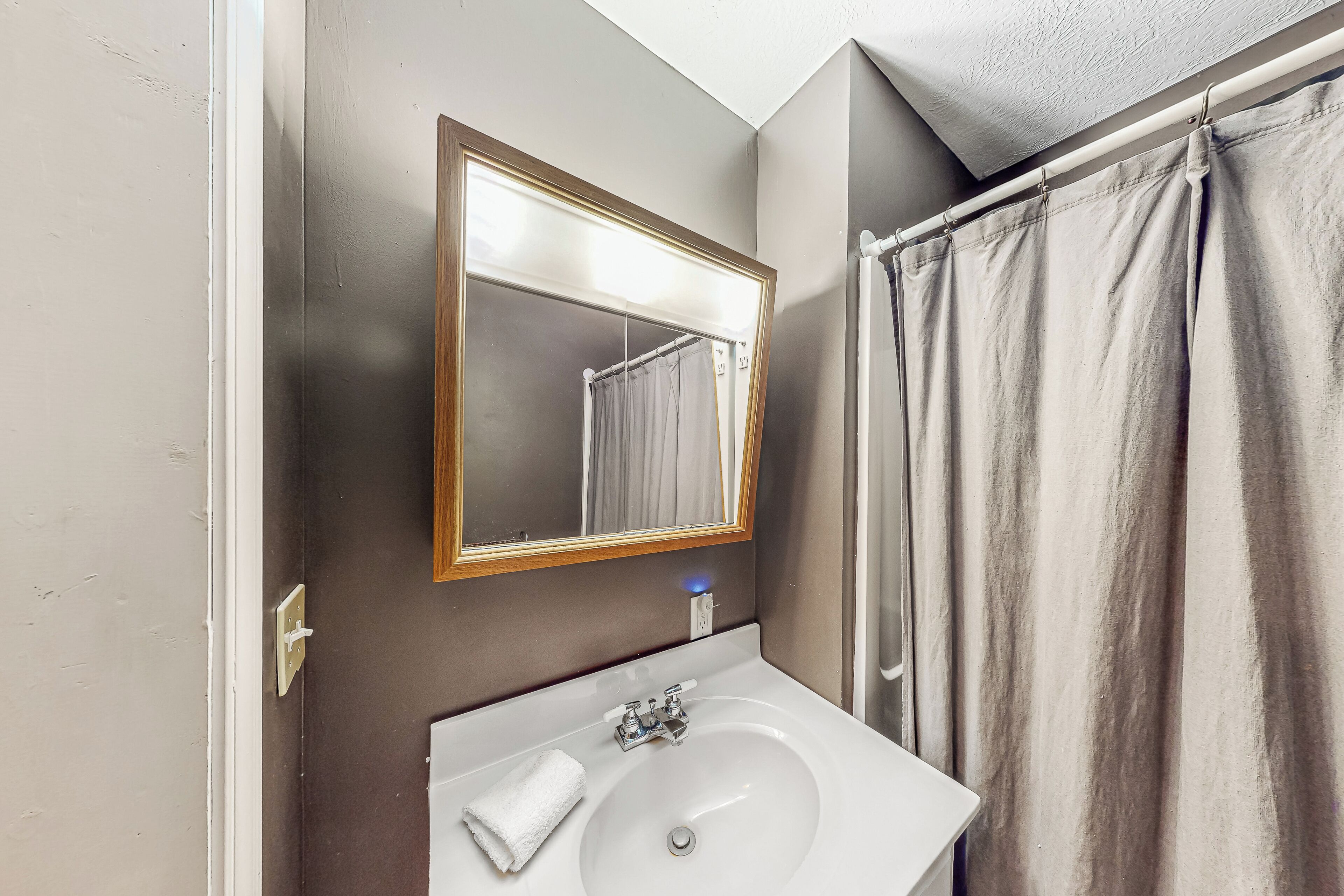 A bathroom with a white sink, a mirror with a wooden frame, and a shower curtain.