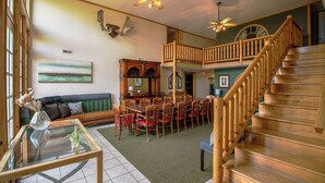 A spacious living area with a dining table, chairs, a sofa, and a staircase. - Hot Tub, Lake Monroe Views! 22-acre Outdoor Oasis (Bloomington)