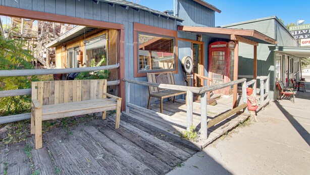 A rustic wooden building with a porch, a vintage telephone booth, and a wooden bench. - Walk to Main Street! Mtn-view Getaway in Pioche (Pioche)