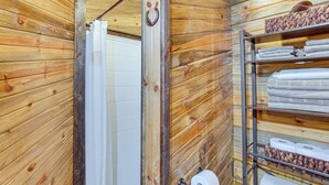 A wooden interior with a shower, a towel rack, and a shelf with towels and toilet paper. - Walk to Main Street! Mtn-view Getaway in Pioche (Pioche)