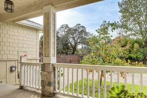A covered porch with a white railing, a brick wall, and a view of a garden with trees and a fence. - Extended Wine Country Stay! Cozy Home in Sonoma (Sonoma)