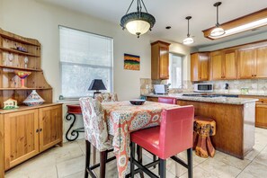 A kitchen with wooden cabinets, a central island, a dining table with chairs, and a hanging light fixture. - Extended Wine Country Stay! Cozy Home in Sonoma (Sonoma)