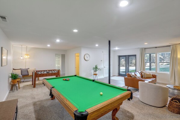 Un grand espace de vie comprenant une table de billard, un canapé et une table à manger.