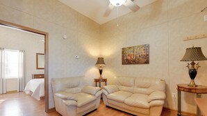 Un salón espacioso con suelo de madera, dos sofás de cuero color beige, una pequeña mesita con una lámpara y un cuadro en la pared.