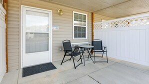 A covered patio with a white door, a small table with two chairs, and a white fence. - Cozy Couples Getaway Near Cataloochee Ski Area! (Waynesville)