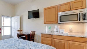 A bedroom with a bed, a desk, and a chair. There is a kitchenette with a microwave, a coffee maker, and a toaster. A television is mounted on the wall. - Cozy Couples Getaway Near Cataloochee Ski Area! (Waynesville)