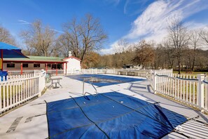 A covered outdoor swimming pool with a blue tarp, surrounded by white fences, and a building with a red roof in the background. - Near Trails & Slopes! Relaxed Waynesville Retreat (Waynesville)