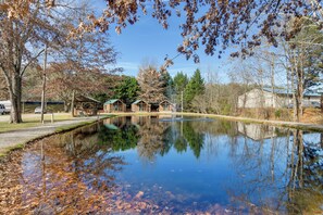 A tranquil pond with reflections of trees and buildings, surrounded by a park with picnic tables and a clear sky. - Near Trails & Slopes! Relaxed Waynesville Retreat (Waynesville)