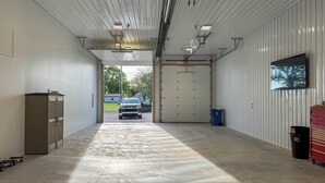 A spacious garage with a concrete floor, a large door, and a vehicle parked outside. - Patio & Parking! Modern Bunkhouse Near Lake Erie (Oak Harbor)