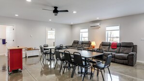 A spacious living room with a large table and chairs, a sofa, and a red cart. - Patio & Parking! Modern Bunkhouse Near Lake Erie (Oak Harbor)