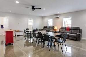 A spacious living room with a large table and chairs, a sofa, and a red cart. - Patio & Parking! Modern Bunkhouse Near Lake Erie (Oak Harbor)